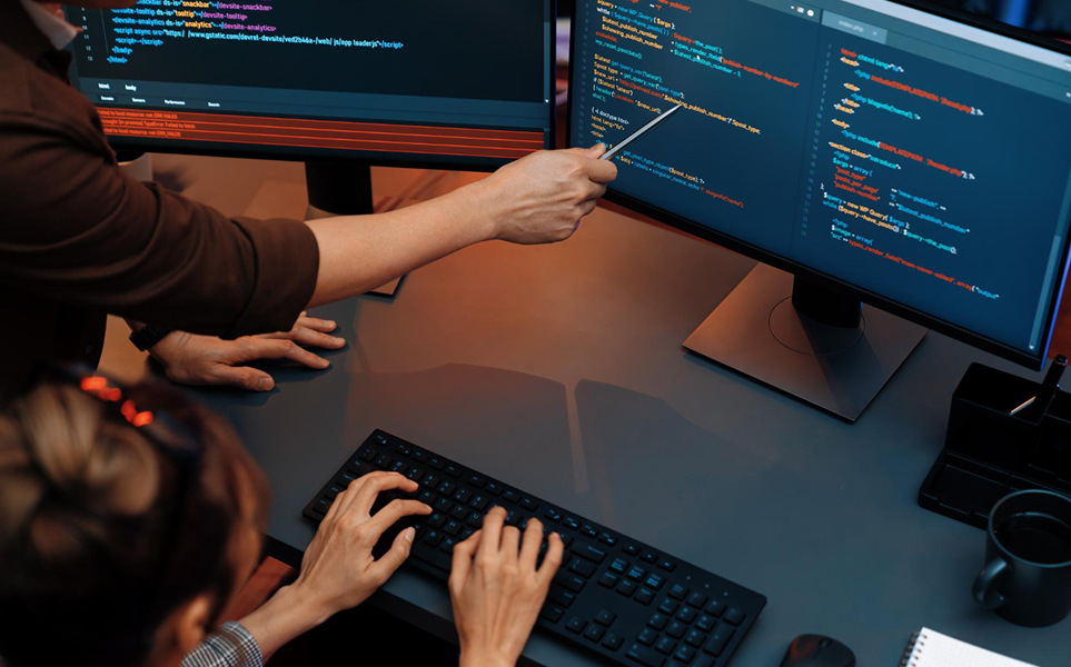 Person pointing at screen whilst code is being written.